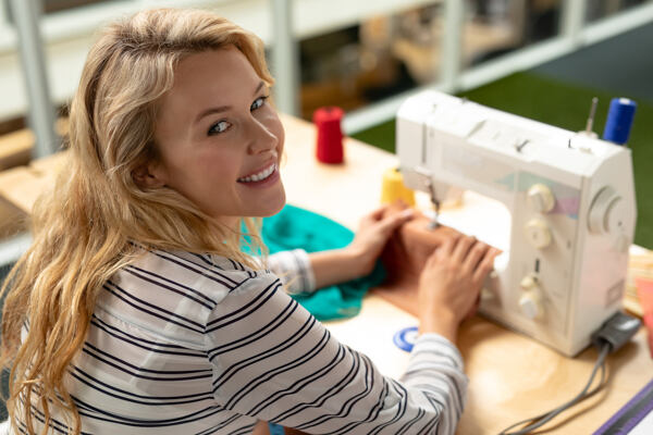 žena u šicího stroje, šije, barevné nitě